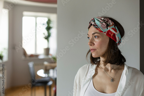 Mature woman wearing headband standing in front of wall at home