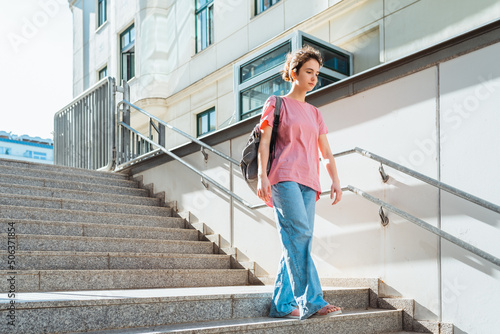 teenager girl, student of gymnasium, with backpack, steps down stairs in rays of sun