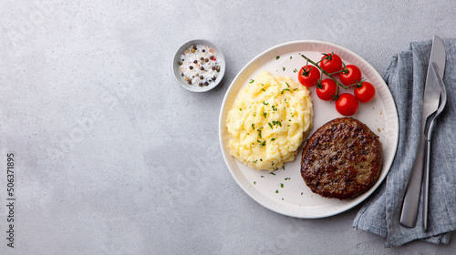 Beefsteak with mashed potato on a plate. Grey background. Copy space. Top view.