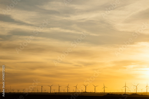 Wind turbines under yellow sky at sunset
