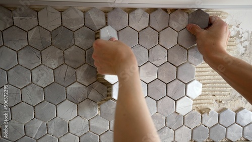 Laying mosaic tiles by the hands of a master. Mosaic tile gluing. The master glues mosaic ceramic tiles on the wall. photo