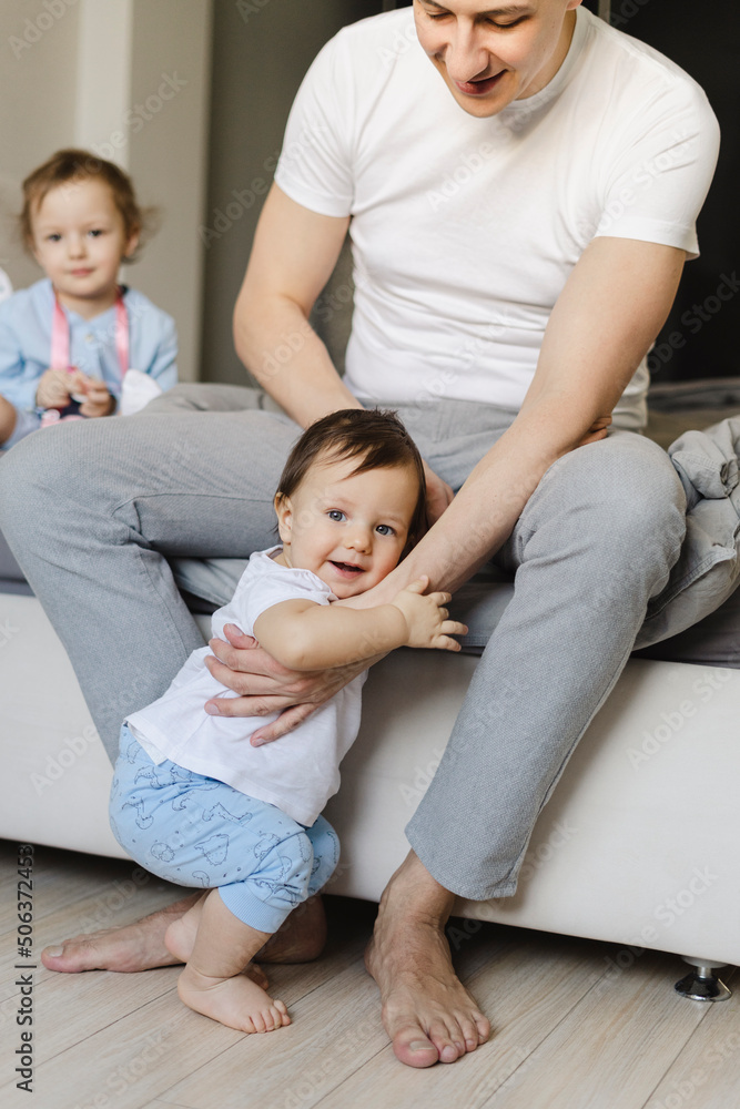 Father holding son sitting by daughter in bedroom