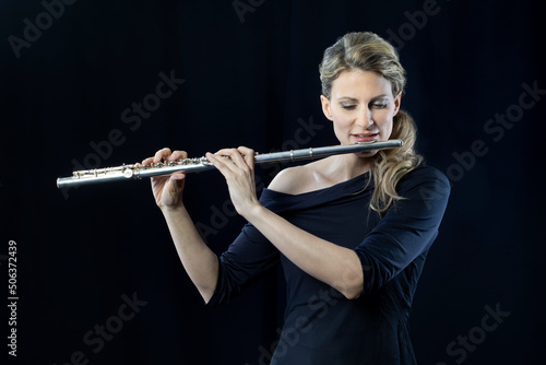 Mature woman playing flute against black background photo