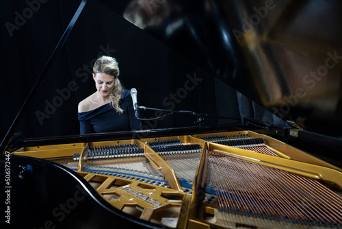 Mature pianist playing grand piano against black background