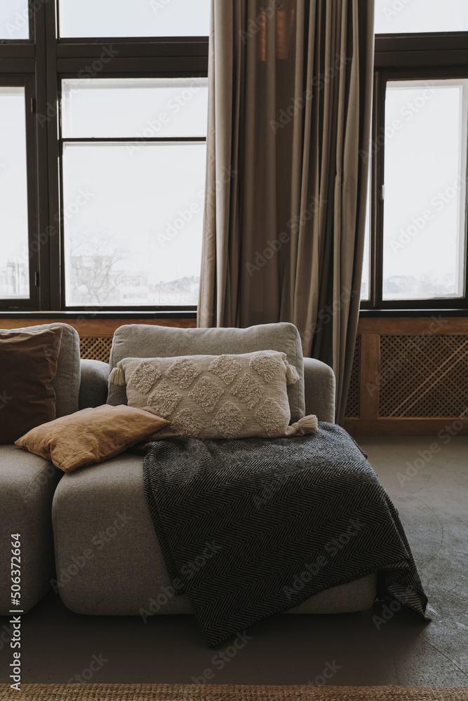 Fototapeta premium Aesthetic modern Scandinavian home interior design. Elegant bohemian living room with comfortable sofa, pillows, windows, curtains, plaid, marble side table