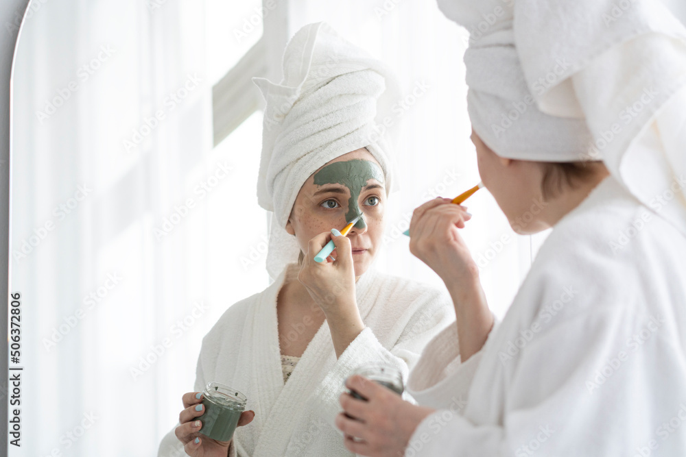 Woman with brush applying facial mask on face at home Woman with brush applying facial mask on face at home