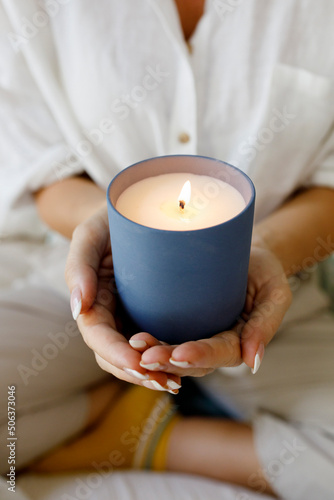 Hands of woman holding scented candle at home photo