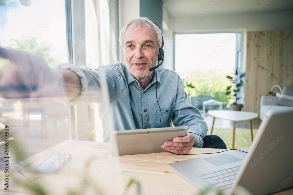 Freelancer wearing headset touching transparent screen at home Freelancer wearing headset touching transparent screen at home
