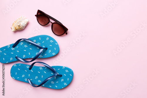 Summer travel concept. Flip flops, sunglasses and starfish on white. Top view on colored background