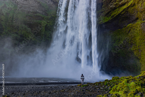 Small person in front of a waterfall