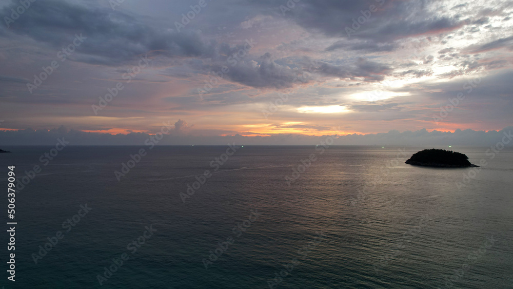 The red-orange sunset is reflected with clouds in the sea. An island can be seen in the distance. Smooth water is like a mirror. There is a lonely island. The green lights of fishing boats are shining The red-orange sunset is reflected with clouds in the sea. An island can be seen in the distance. Smooth water is like a mirror. There is a lonely island. The green lights of fishing boats are shining