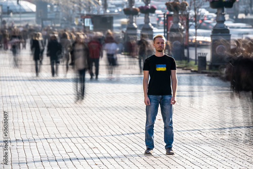 The young man stands in the middle of crowded street. © Artem