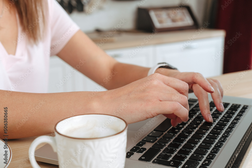 Businesswoman hand working at a home. woman using laptop, female hands typing, writing notes, studying languages, distance learning concept, checking email in morning, drink coffee Businesswoman hand working at a home. woman using laptop, female hands typing, writing notes, studying languages, distance learning concept, checking email in morning, drink coffee