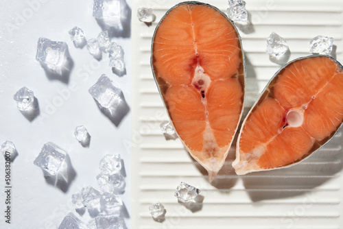 frozen salmon red fish steaks on a white plate with ice on a white background