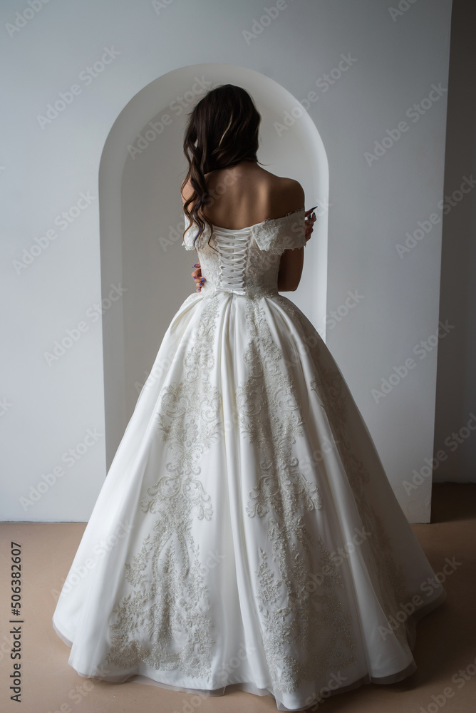 Fototapeta premium Beautiful bride posing in wedding dress in a white photo Studio.