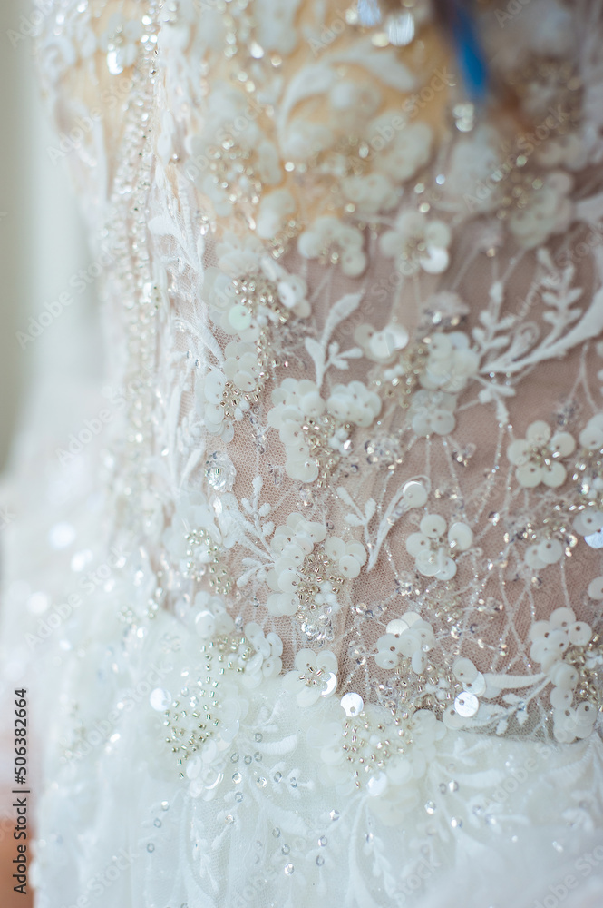 Bride at the clothes shop for wedding dresses; she is choosing a dress and the designer is assisting her Bride at the clothes shop for wedding dresses; she is choosing a dress and the designer is assisting her