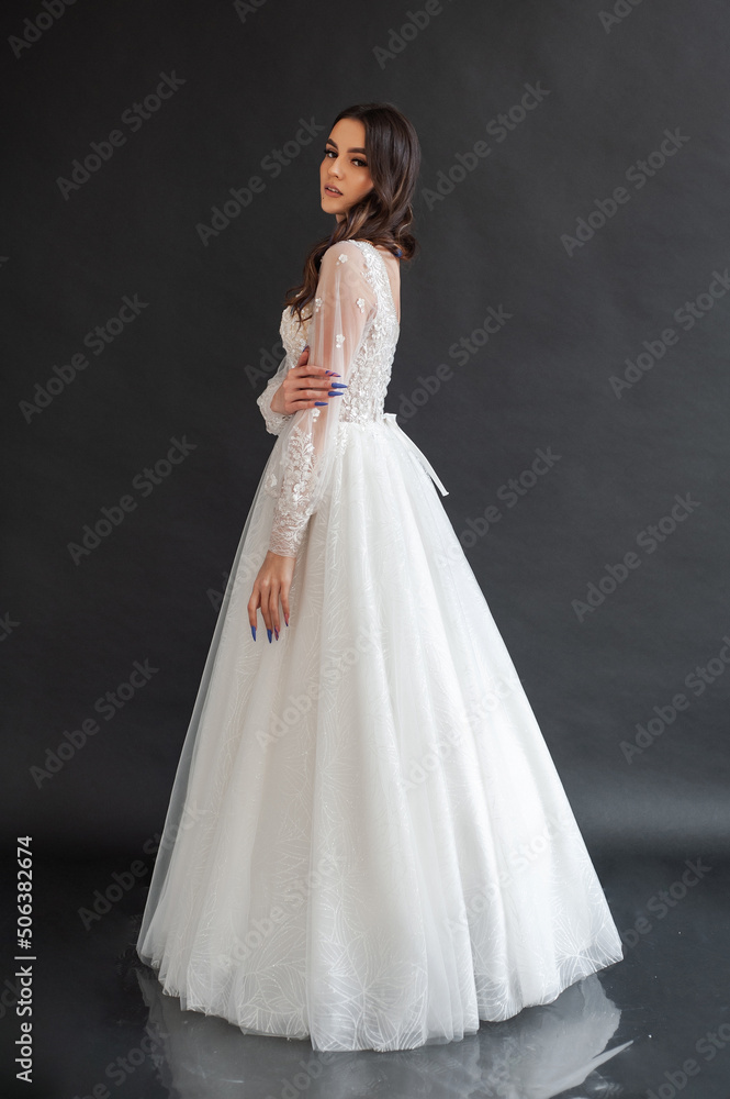 Beautiful bride in a magnificent white wedding dress of tulle with corset lacing and long beauty hair Beautiful bride in a magnificent white wedding dress of tulle with corset lacing and long beauty hair