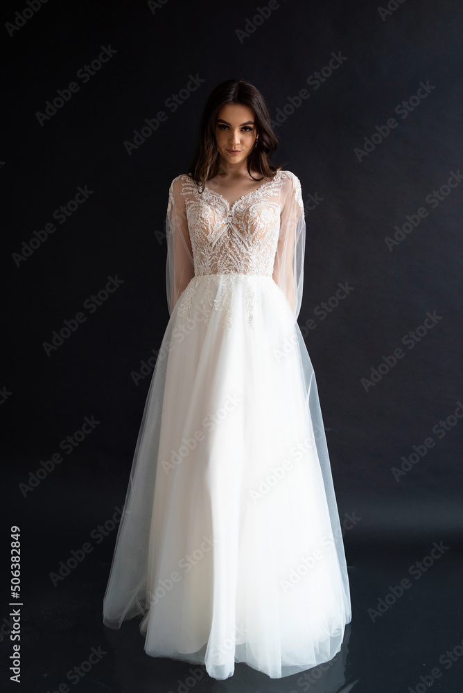 Full length portrait of young beautiful woman wearing white wedding dress. Elegant bride standing and posing Full length portrait of young beautiful woman wearing white wedding dress. Elegant bride standing and posing