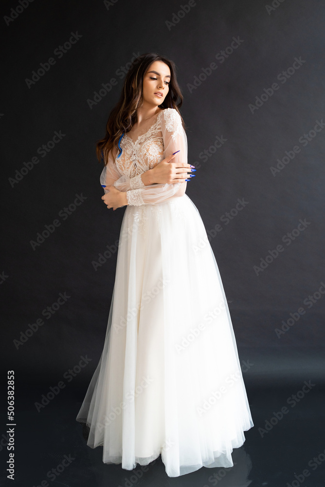 Full length portrait of young beautiful woman wearing white wedding dress. Elegant bride standing and posing Full length portrait of young beautiful woman wearing white wedding dress. Elegant bride standing and posing