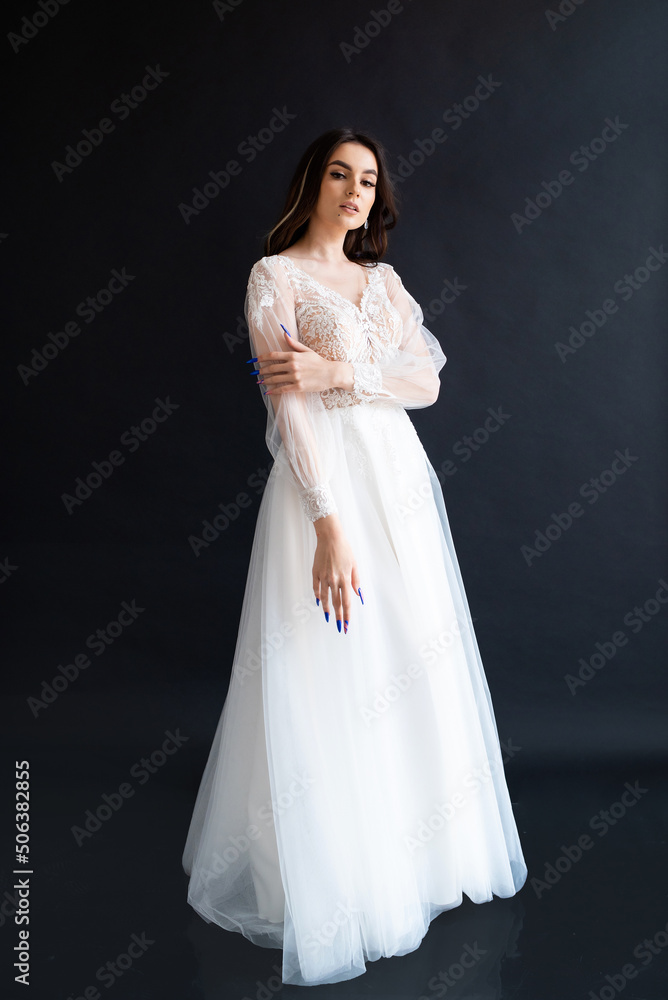 Full length portrait of young beautiful woman wearing white wedding dress. Elegant bride standing and posing