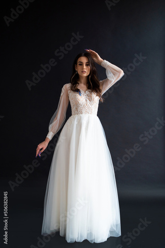 Full length portrait of young beautiful woman wearing white wedding dress. Elegant bride standing and posing