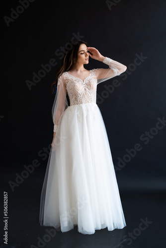 Full length portrait of young beautiful woman wearing white wedding dress. Elegant bride standing and posing