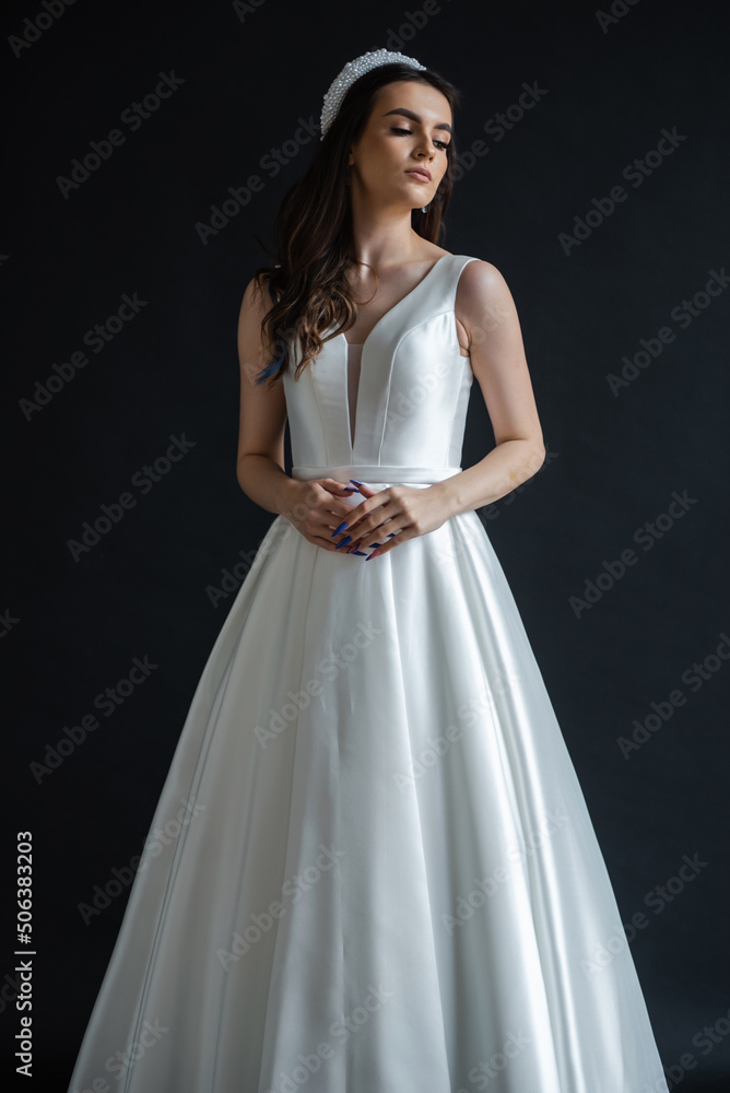 Charming young bride in luxurious wedding dress. Pretty girl in white. Emotions of happiness, laughter and smile, gray background Charming young bride in luxurious wedding dress. Pretty girl in white. Emotions of happiness, laughter and smile, gray background