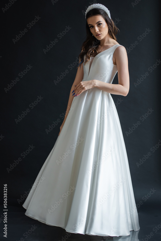 Charming young bride in luxurious wedding dress. Pretty girl in white. Emotions of happiness, laughter and smile, gray background Charming young bride in luxurious wedding dress. Pretty girl in white. Emotions of happiness, laughter and smile, gray background