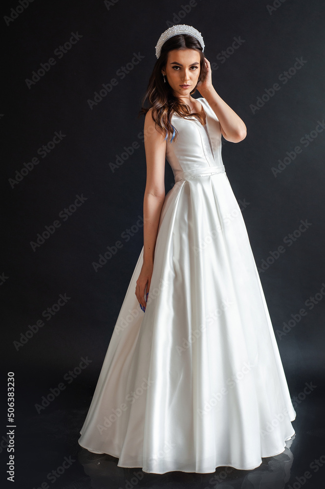 Charming young bride in luxurious wedding dress. Pretty girl in white. Emotions of happiness, laughter and smile, gray background