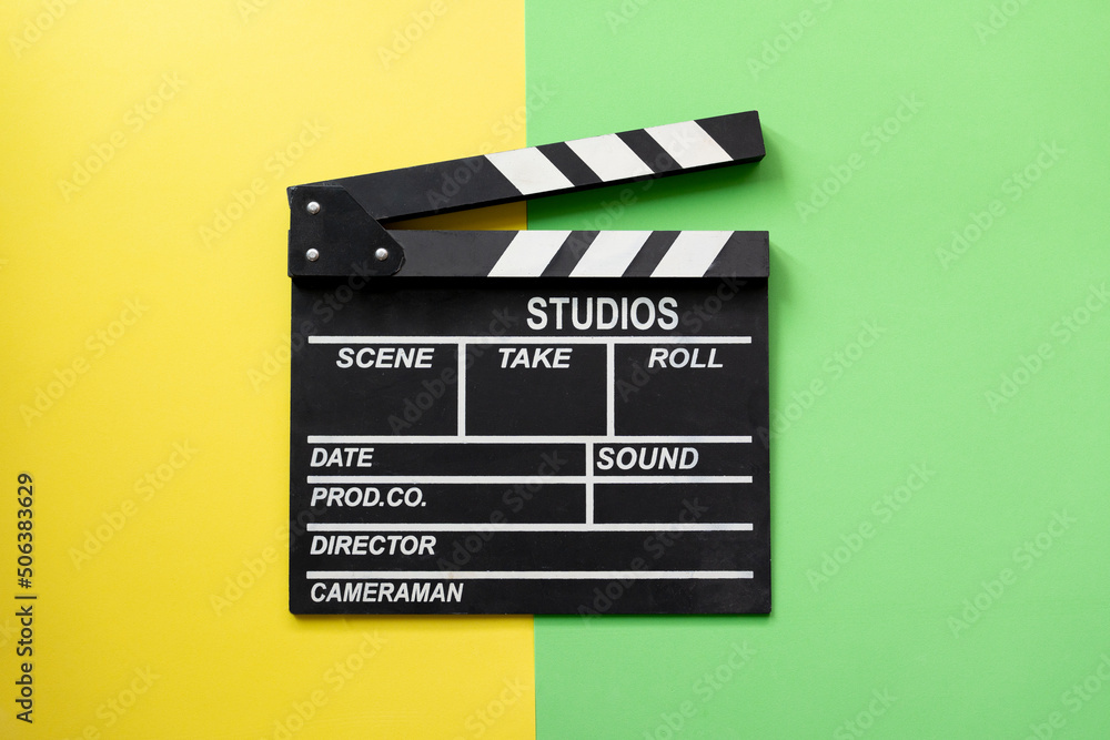 movie clapper on yellow and green table background ; film, cinema and video photography concept