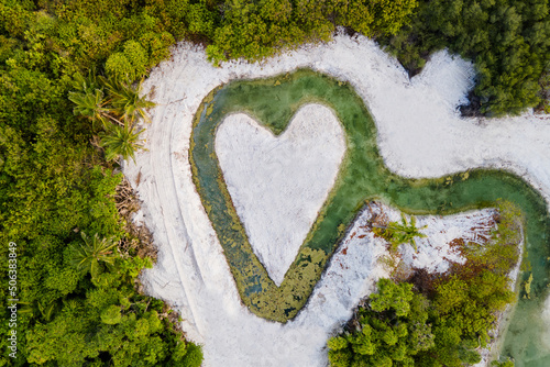 Aerial view of heart-shaped pond and white sand beach on tropical island of Maldives