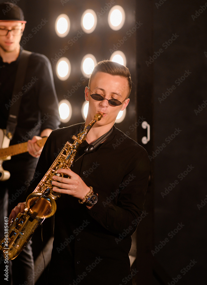 Naklejka premium Young saxophone playing the saxophone on a loft interior background with light bulbs