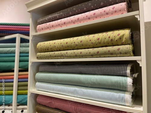 A collection of colorful fabrics with various motifs in the wardrobe. A clothing store wardrobe with multi-storey shelves looks luxurious with a design like a minimalist home interior.
