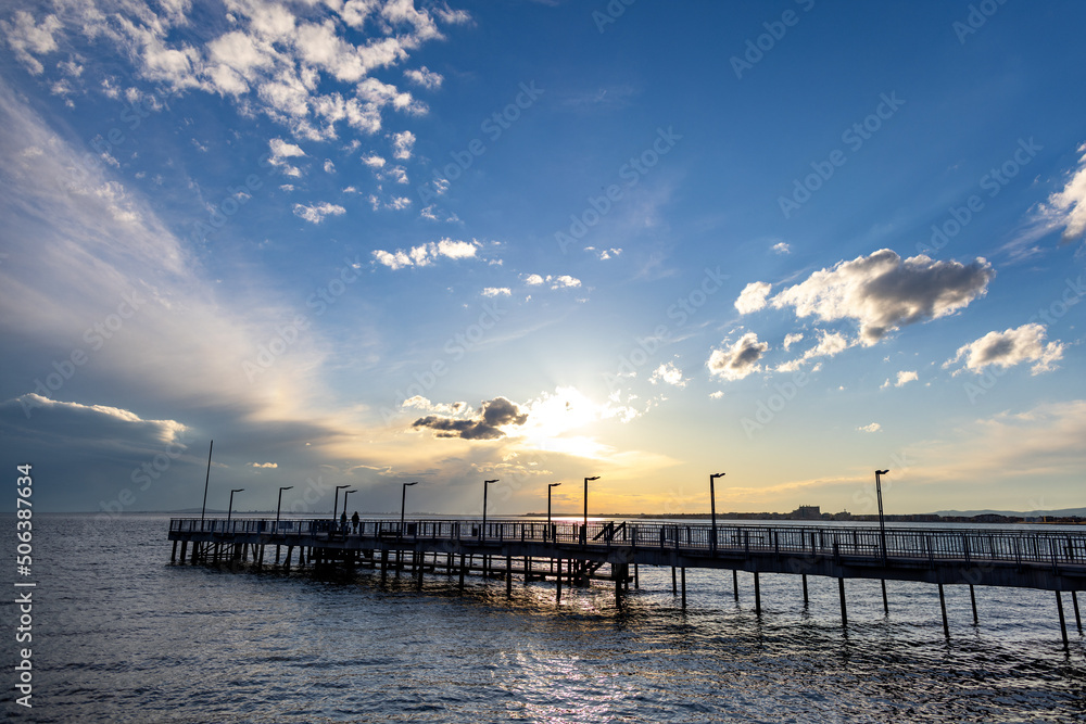 Side view of the pier on the Black Sea against the background of the sky and sunset