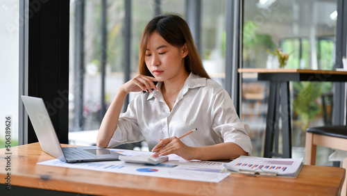 Millennial Asian female business college student doing her finance homework