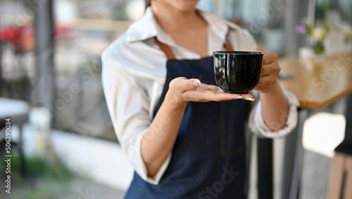 Cropped image, Female barista holding a black cup of coffee © bongkarn