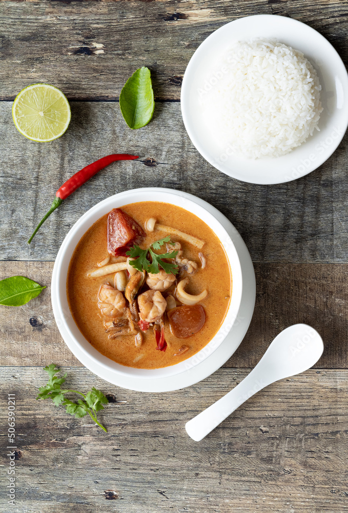 Top view of traditional Thai food. Thai and lao traditional soup - tom yam with seafood on a wooden table with chili, kaffir, lime and coriander. Top view of traditional Thai food. Thai and lao traditional soup - tom yam with seafood on a wooden table with chili, kaffir, lime and coriander.