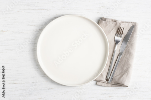 Fotografie, Obraz White empty plate and silver cutlery on linen napkin on white wooden table