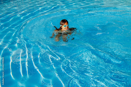 Jeune fille nageant heureuse dans une piscine avec des lunettes