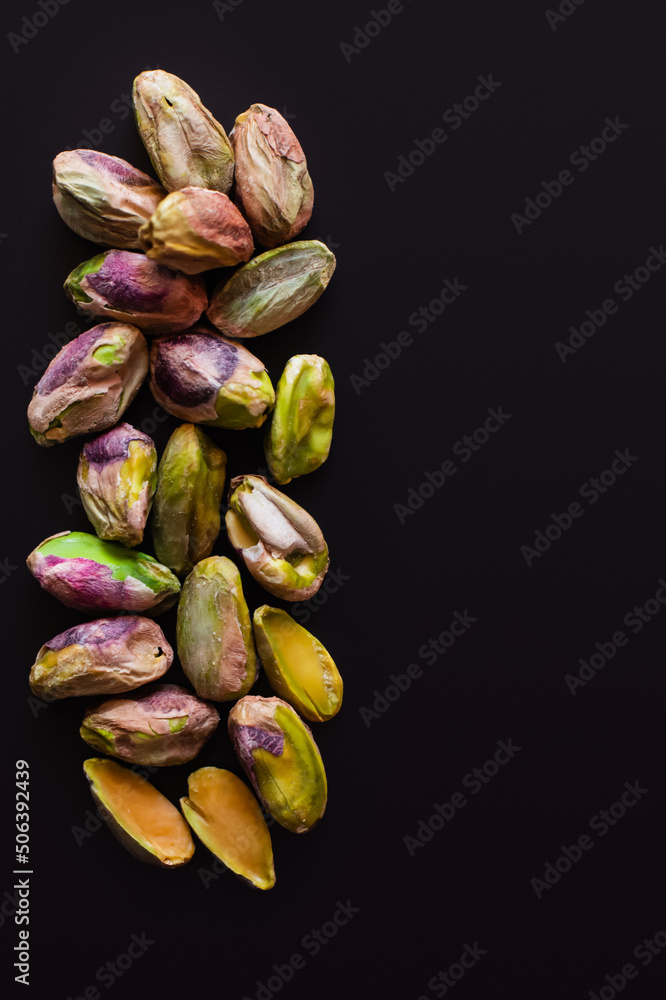 Obraz premium top view of green and salty pistachios without shell isolated on black