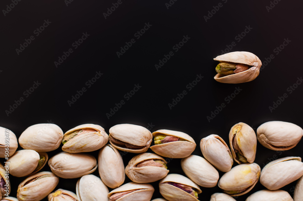 top view of tasty and natural pistachios with salt isolated on black top view of tasty and natural pistachios with salt isolated on black