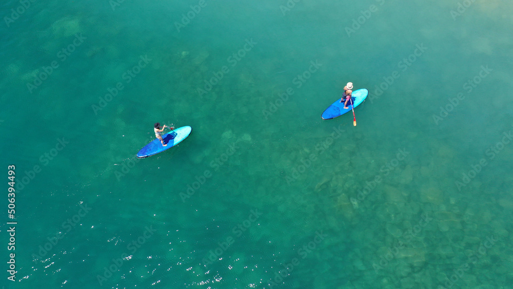 Aerial drone view of couple exercising sup board in turquoise tropical clear open sea Aerial drone view of couple exercising sup board in turquoise tropical clear open sea