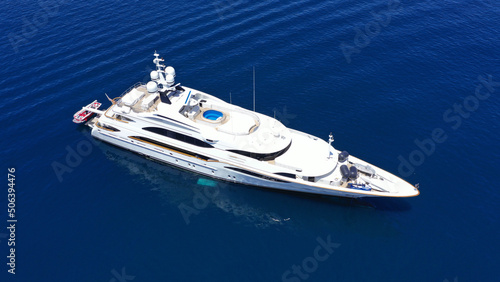 Aerial drone photo of large yacht with wooden deck anchored in Aegean island deep blue sea