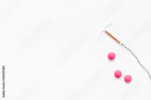 Contraception concept. T-shaped intrauterine contraceptive with medicine pills © 9dreamstudio