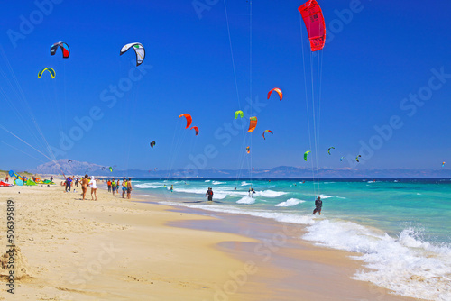 Tarifa, (Costa de la luz, Playa de Bolonia), Spain - Beautiful atlantic ocean sand beach, turquoise water, waves, kite surfers, blue sky, blurred african continent  photo