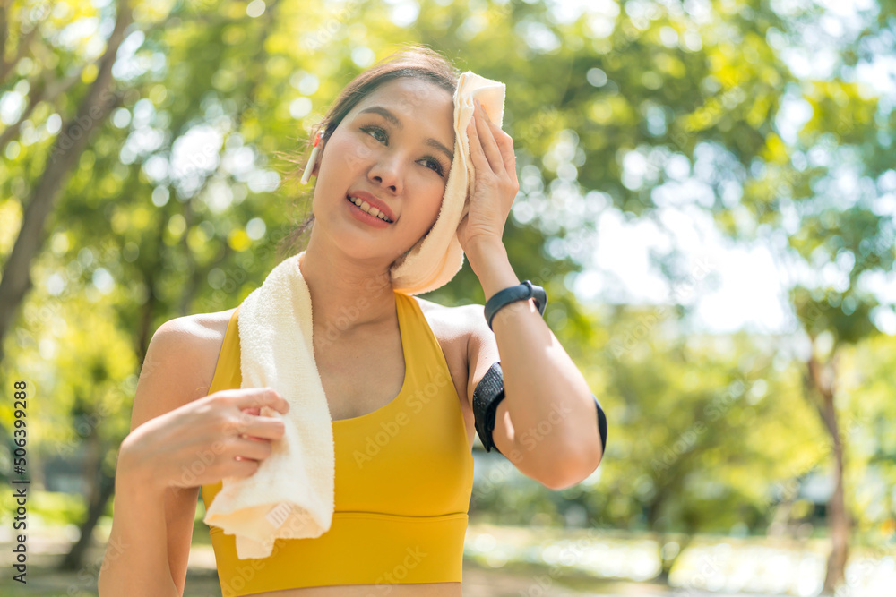 Asian active Female runner workout standing bent over and catching her breath after a running session in the park garden. Sports female woman taking break after a run in morning exercise lifestyle