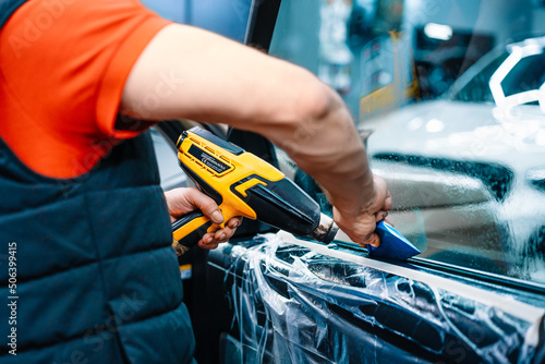 Professional worker installing ceramic film on car window