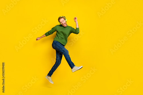 Full length photo of dreamy funny guy dressed sweater earphones enjoying music dancing empty space isolated yellow color background