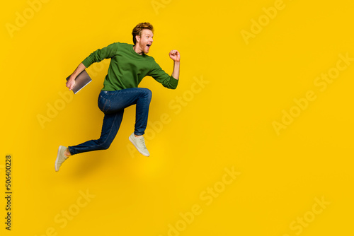 Full length photo of charming sweet man wear pullover fist walking modern gadget empty space isolated yellow color background
