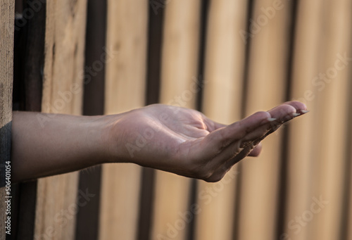 Hand begging for money from behind a fence. Concept. Problems of the hungry and proverty. Economic problems.